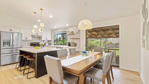 A modern kitchen with a central island, bar stools, and pendant lighting. - Spacious Modern Retreat w Game Room and Yard (Lynnwood)