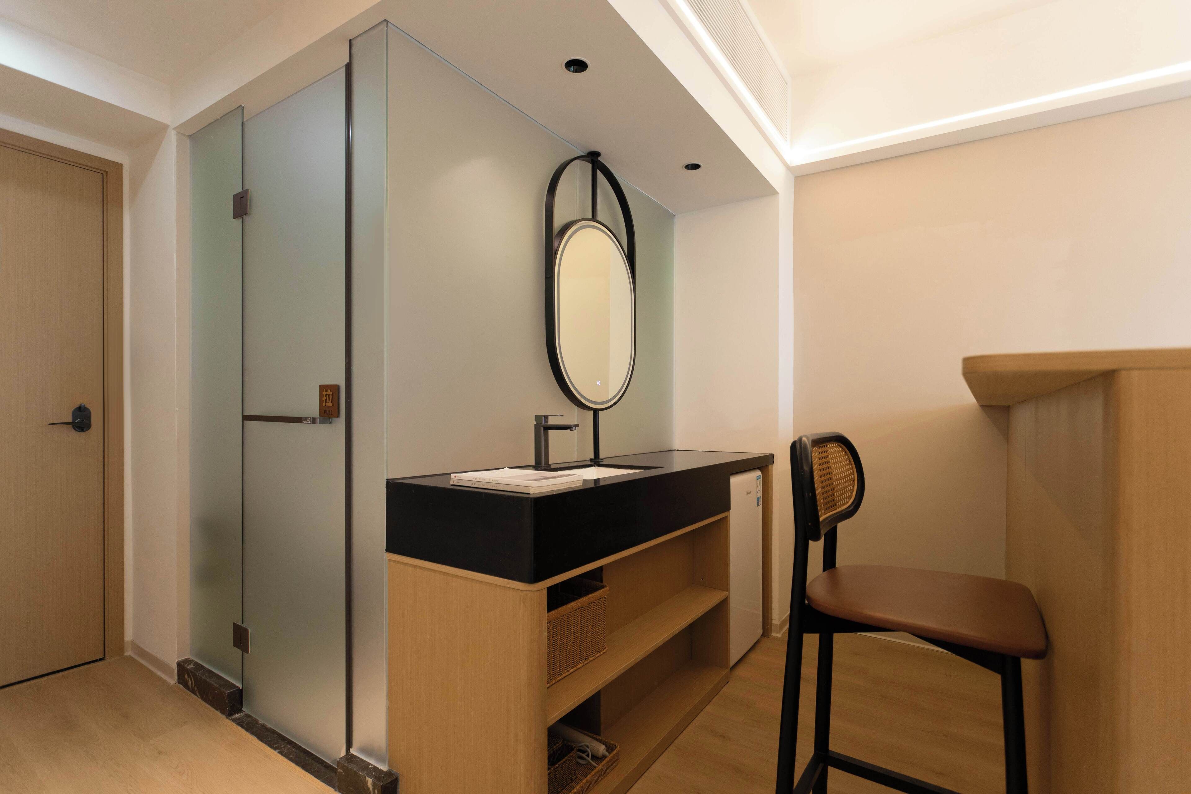 A modern bathroom with a black sink, mirror, and wooden vanity.