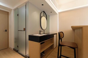 Un baño moderno con lavamanos negro, espejo y tocador de madera.