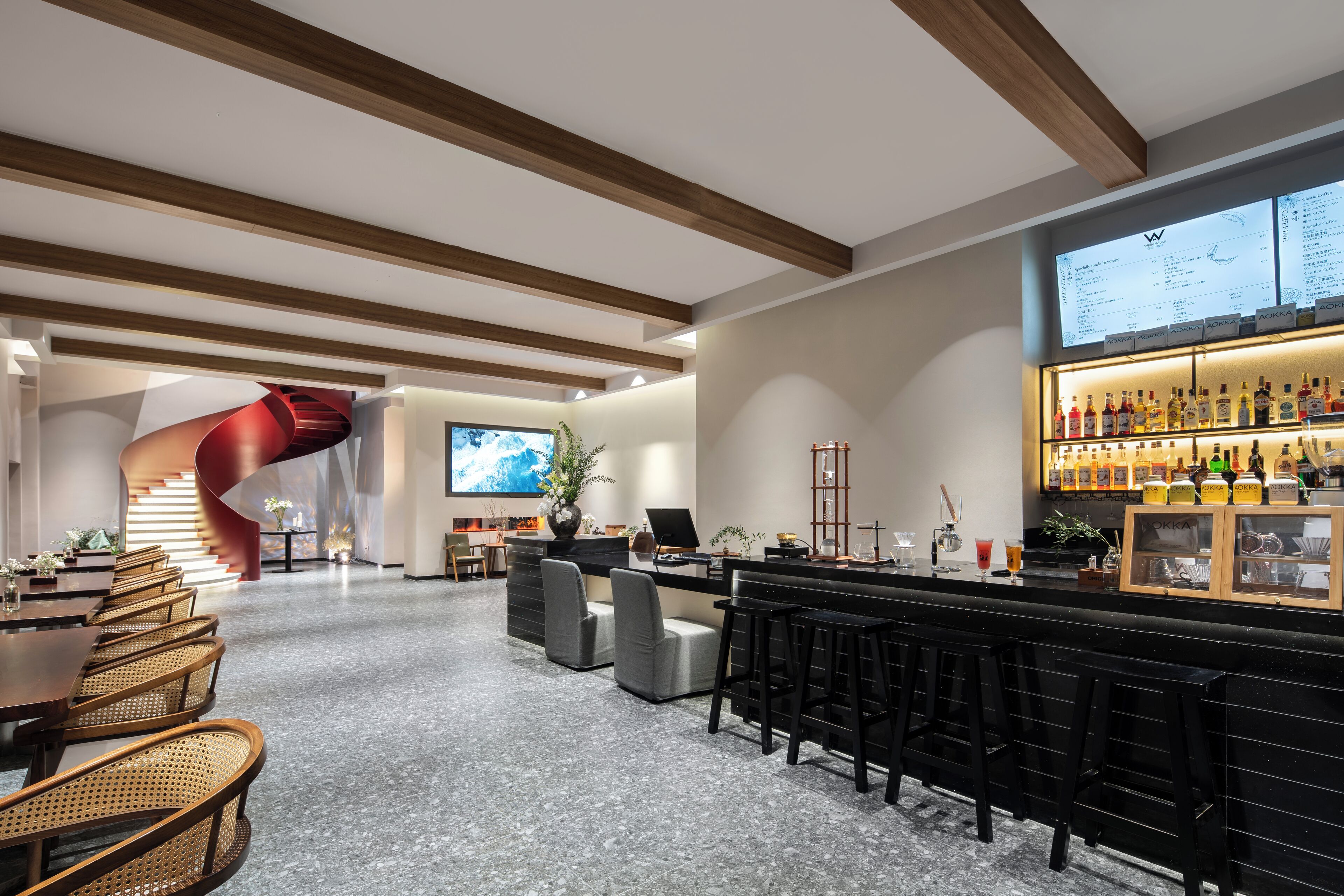 A modern bar area with a curved staircase, seating arrangements, and a bar counter with various bottles.