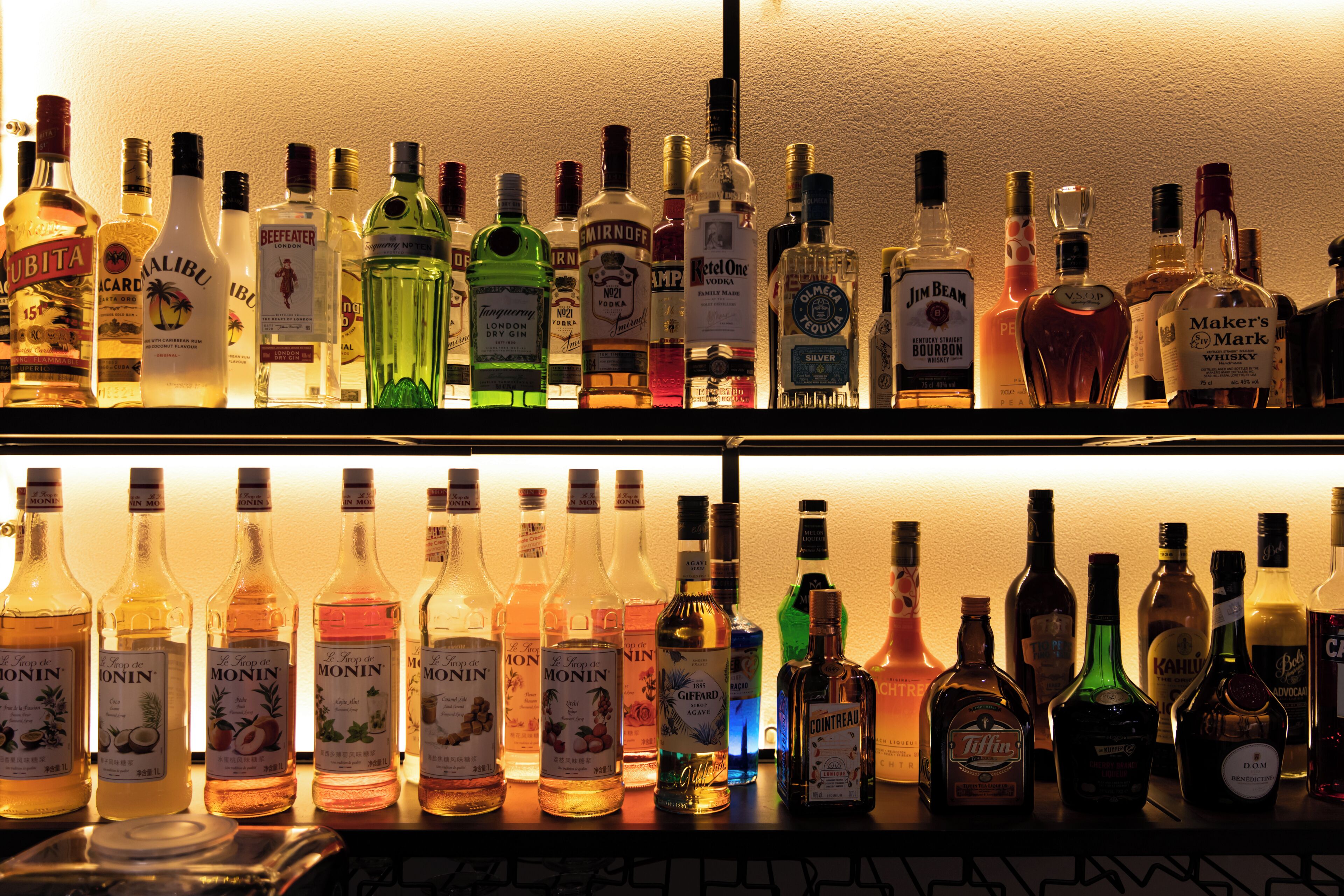 A bar with multiple shelves of various liquor bottles.