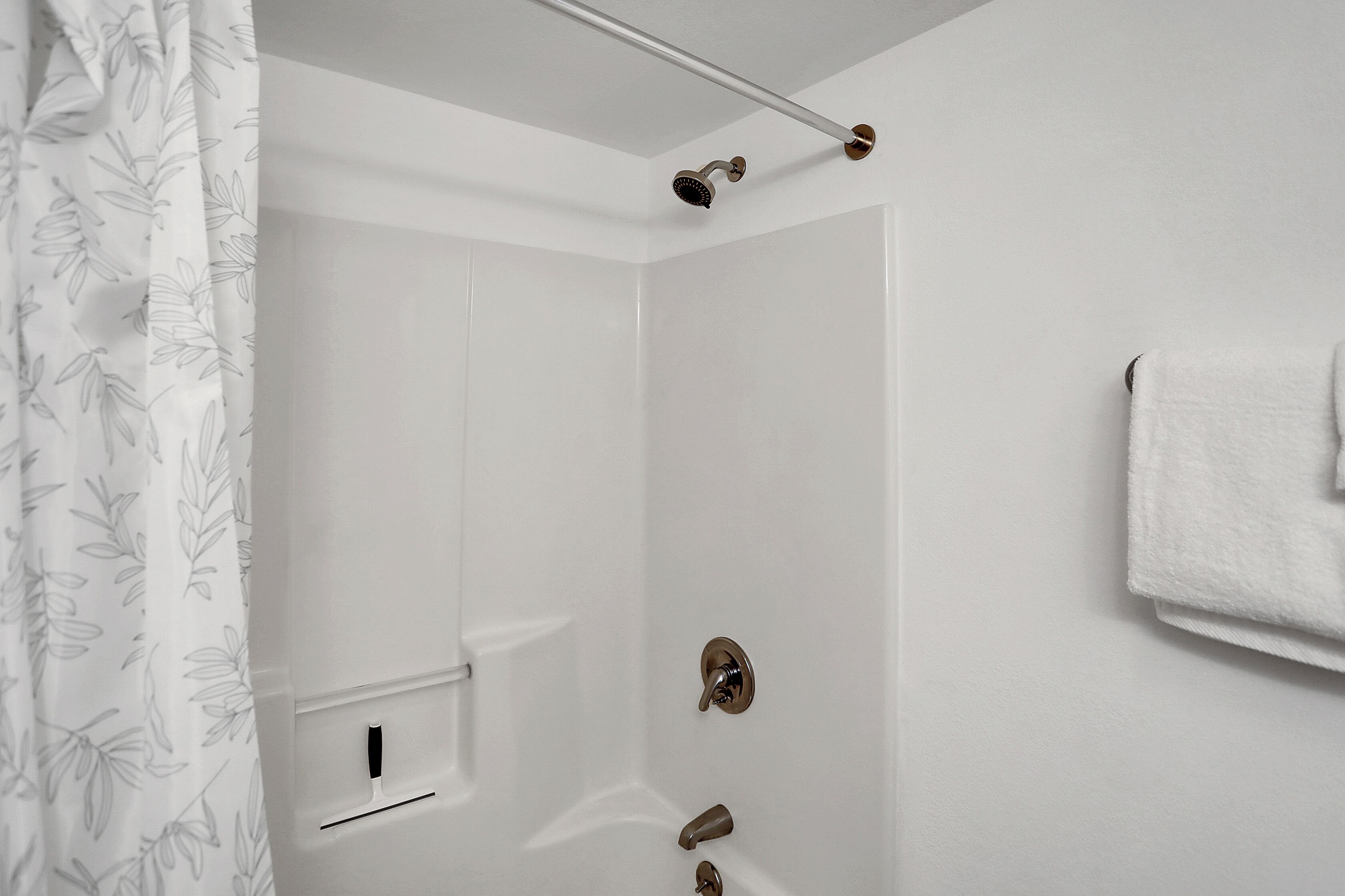 A modern bathroom with a shower, a towel rack, and a toilet paper holder.