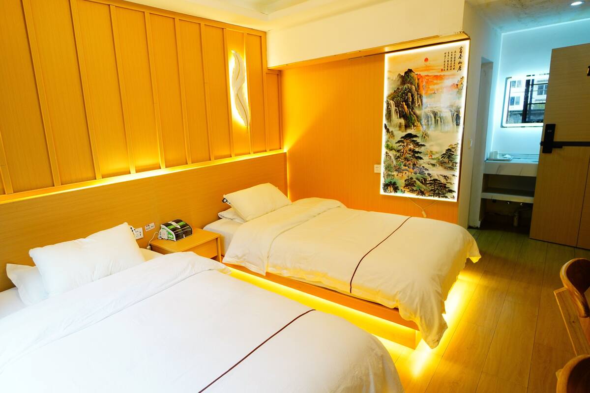 Een hotelkamer met twee bedden, houten lambrisering, een kunstwerk aan de muur en een zichtbare badkamer.