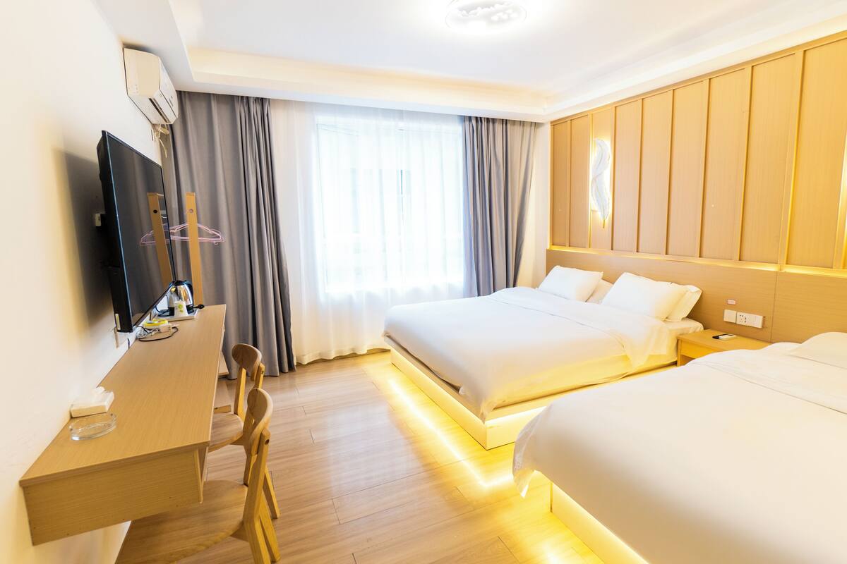 Een hotelkamer met een groot bed, een bureau met een stoel, een televisie en een raam met gordijnen.