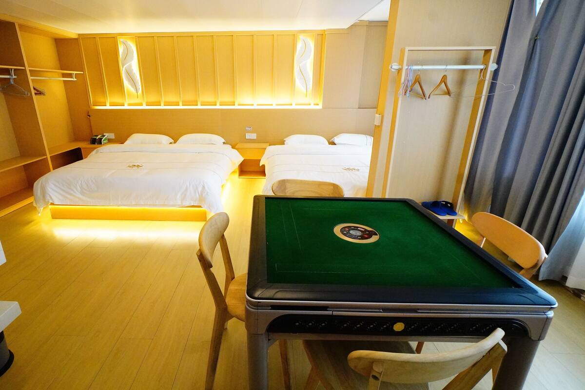 Een hotelkamer met twee bedden, een pooltafel, een bureau en een kledingkast.