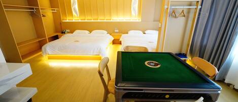 A hotel room with two beds, a pool table, a desk, and a wardrobe.