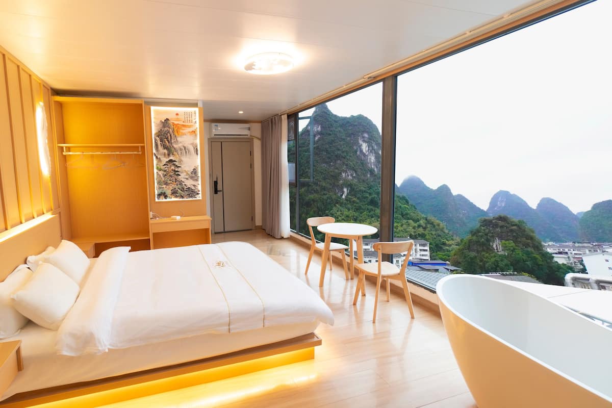 Een moderne hotelkamer met een groot bed, een badkamer met een bad en uitzicht op bergen.