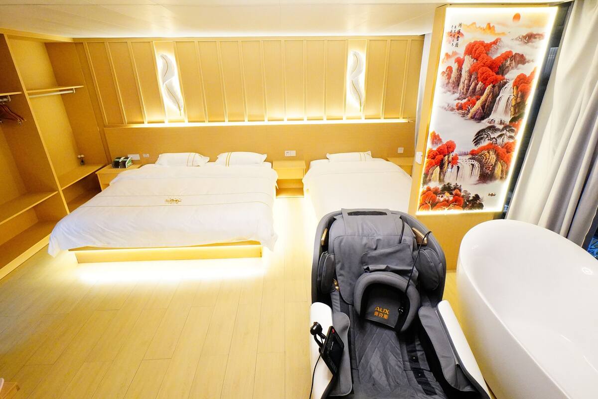 Hotelkamer met een groot bed, een zithoek, een badkuip en een kunstwerk aan de muur.