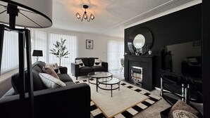A modern living room with a black sofa, a round coffee table, and a fireplace. - Paddock View - Snetterton, Norfolk (norwich)