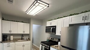 A modern kitchen with white cabinets, stainless steel appliances, and a wooden floor. - Cozy, 1-bedroom apartment with a pulled-out couch, close to all the facilities. (Porterville)