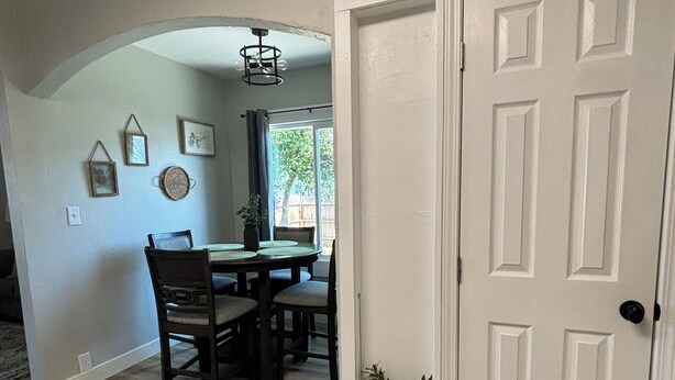 A dining area with a wooden table and chairs, a white door, and a small potted plant. - Cozy, 1-bedroom apartment with a pulled-out couch, close to all the facilities. (Porterville)