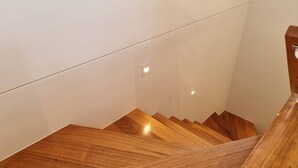 Un escalier en bois au design moderne, menant à un étage supérieur.