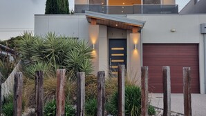 Une maison moderne à deux étages, dotée d’un garage, d’un balcon et d’un jardin bien entretenu.