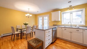 A kitchen with white cabinets, a dining table with chairs, and a chandelier.