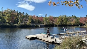 A wooden dock extending into a calm lake surrounded by autumn-colored trees.