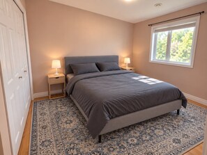 Une chambre à coucher avec un lit, des tables de chevet, une fenêtre et une porte.