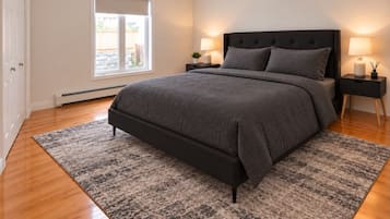 A bedroom with a bed, two bedside tables, a window, and a door.