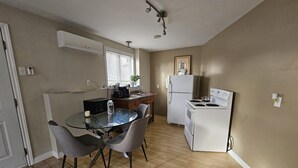 Kompakti keittiö, jossa on ruokapöytä, tuolit, jääkaappi ja liesi.