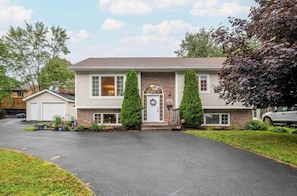 A two-story house with a front porch, a garage, and a driveway. - Cozy 2-Bedroom Basement unit (Dartmouth)