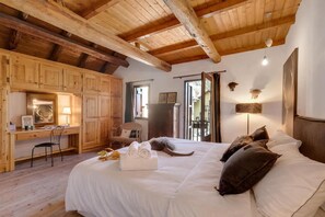 Una habitación acogedora con una cama grande, vigas de madera en el techo, un escritorio y una silla.