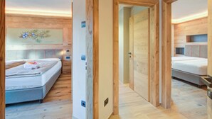 A modern hotel room with wooden flooring, a large mirror, and a bed with a white mattress and pillows. - New Ginepro Ski 10 m, Livigno, Italy (Livigno)