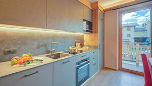 A modern kitchen with a built-in oven, a sink, and a countertop with fresh vegetables. - New Ginepro Ski 10 m, Livigno, Italy (Livigno)