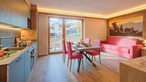 A modern kitchen with a dining area, a red sofa, and a painting of a mountain scene. - New Ginepro Ski 10 m, Livigno, Italy (Livigno)