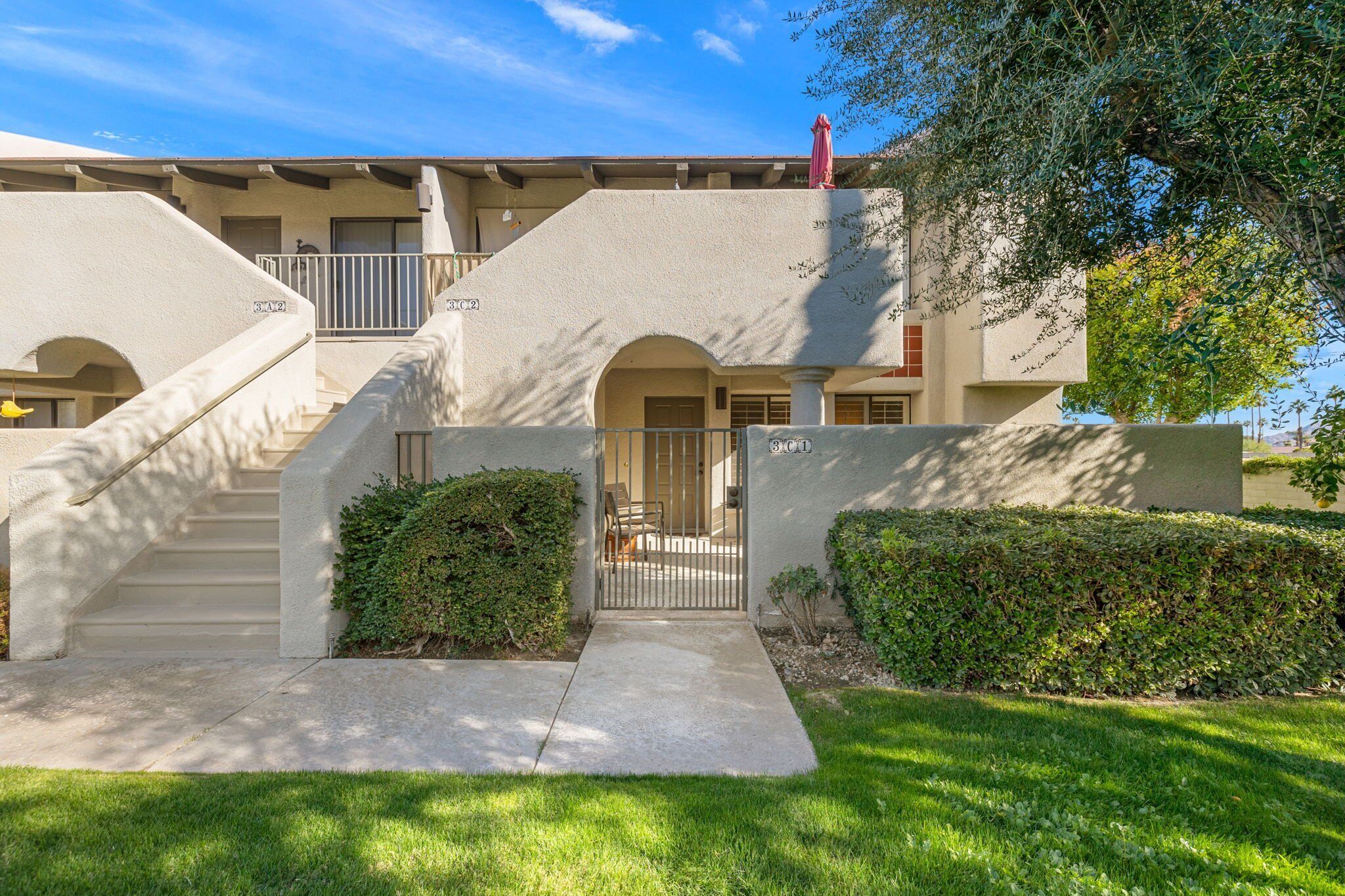 A two-story building with a covered front porch, a staircase leading to the upper level, and a gated entrance.