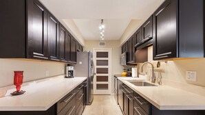 A modern kitchen with dark cabinets, a white countertop, and a central island.