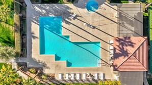 An aerial view of a swimming pool area with a large pool, sun loungers, and a small fountain.