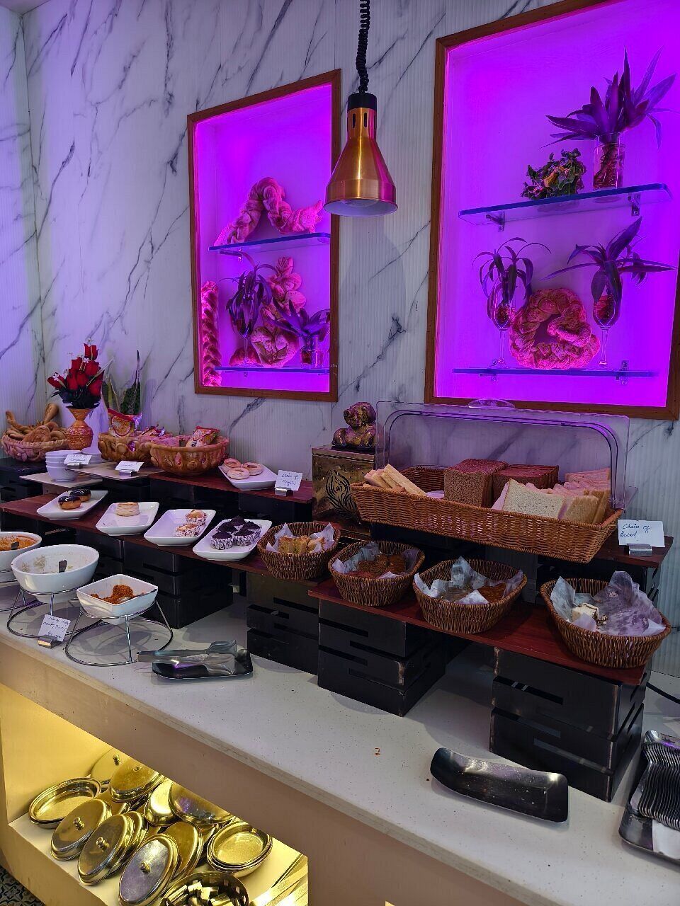A buffet setup with various food items and decorative plants.
