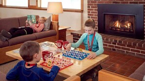 Ein gemütliches Wohnzimmer mit Kamin, einer Couch, einem Couchtisch mit einem Puzzle und einem spielenden Kind.