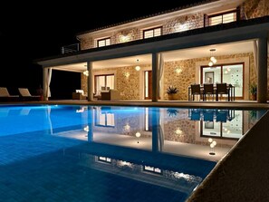 A modern hotel with a swimming pool, stone walls, and a dining area with outdoor seating. - Ca`n Mutxo, stunning views, swimming pool and barbecue (Biniamar)