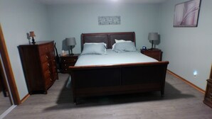 Un dormitorio con una cama grande, dos mesitas de noche con lámparas, un aparador y un ventilador de techo.