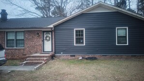 A two-story house with a brick entrance and a dark-colored exterior.