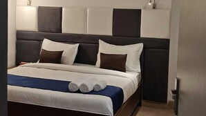 A modern bedroom with a bed, a ceiling fan, and a nightstand. - Nimantrana (Noida)