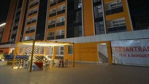 A multi-story building with a prominent yellow facade and a sign advertising a banquet facility. - Nimantrana (Noida)