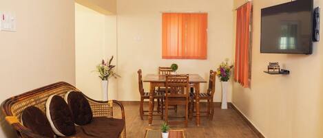 Un salon comprenant un canapé, une table à manger, des chaises, un téléviseur et un ventilateur de plafond.