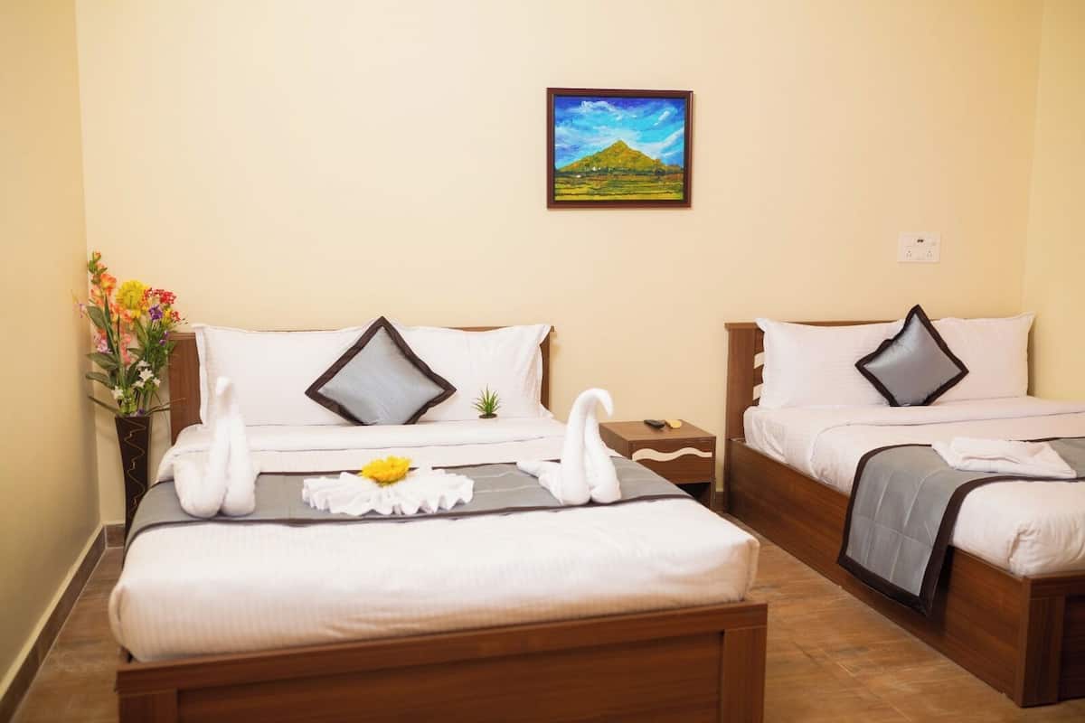 A hotel room with two beds, a painting on the wall, and a vase with flowers on the left side.