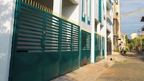 A modern residential building with a white facade and teal accents, featuring balconies and a gated entrance. - RPS Service Apartment (Tiruvannamalai)