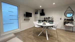 A modern kitchen with white cabinets, a microwave, and a TV mounted on the wall.