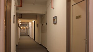 A hotel corridor with doors, light fixtures, and a wall-mounted sign. - Nimantrana (Noida)