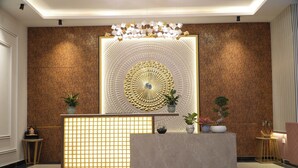A reception area with a marble reception desk, a decorative wall with a circular pattern, and potted plants. - Nimantrana (Noida)