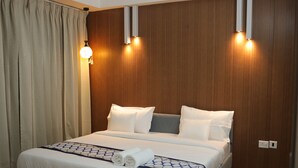 A hotel room with a bed, curtains, and wall-mounted lights. - Nimantrana (Noida)