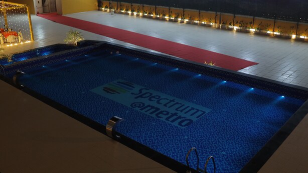 A swimming pool with a red carpet and lights along the edge. - Nimantrana (Noida)