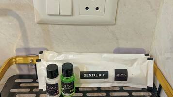 A bathroom with a white wall, a white switchboard, and a black and yellow tray with a dental kit and two bottles.