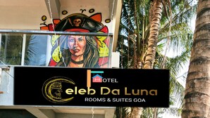 A hotel entrance with a sign for 'Celeb Da Luna' and a tropical garden area with potted plants and palm trees.