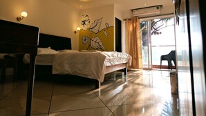 A modern hotel room with a bed, a desk, a ceiling fan, and a large window with curtains.