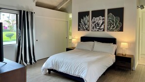 A bedroom with a bed, two bedside tables with lamps, a ceiling fan, and three wall-mounted flower paintings. - Quiet, comfortable 2-bedroom condo at Mission Hills in Rancho Mirage (Rancho Mirage)
