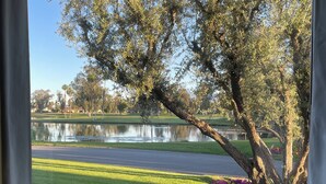 A view of a golf course with a pond, trees, and a clear sky. - Quiet, comfortable 2-bedroom condo at Mission Hills in Rancho Mirage (Rancho Mirage)